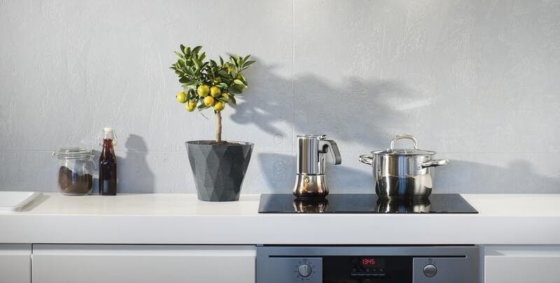 Kettle and saucepan on top of electric cooktop against white wall