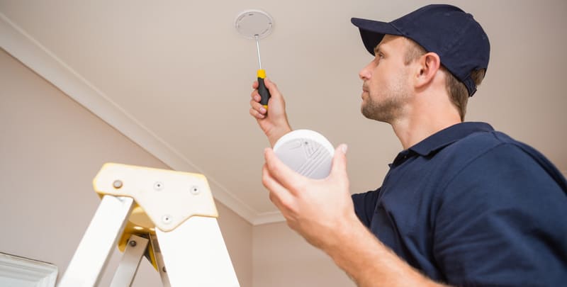 handyman installing smoke detector