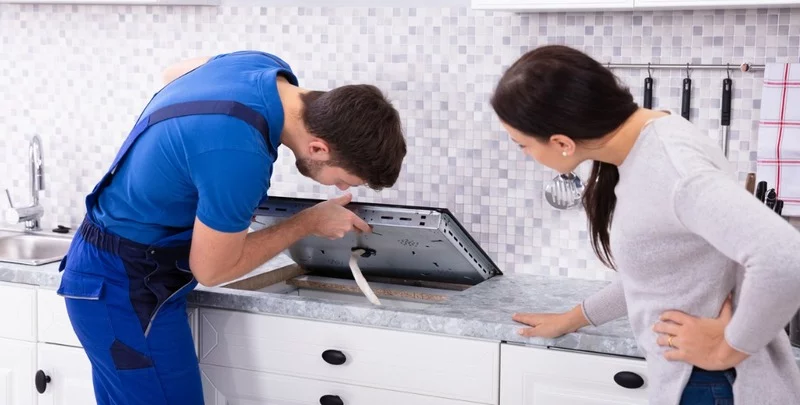 repairman fixing induction stove in the kitchen