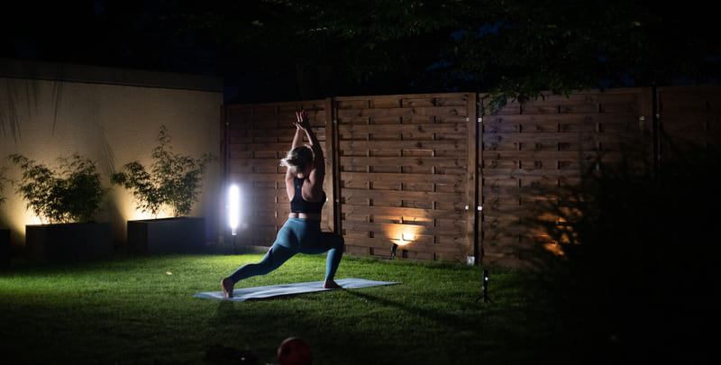 landscape lighting woman in yoga pose at night on backyard lawn
